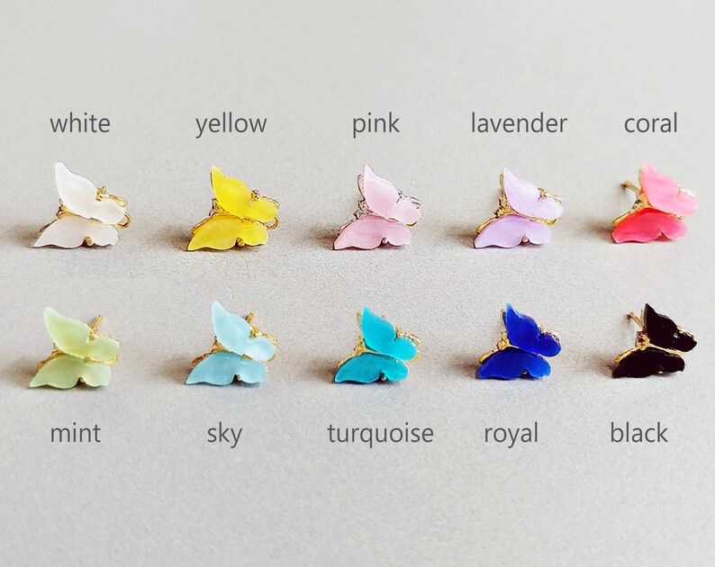 May include: A collection of butterfly-shaped accessories in various colors, including white, yellow, pink, lavender, coral, mint, sky blue, turquoise, royal blue, and black. Each butterfly has gold-colored accents.