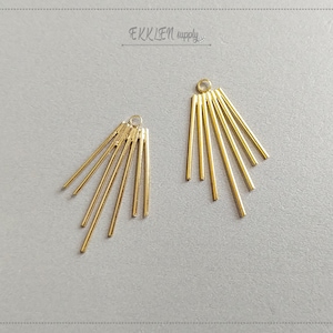 May include: Two gold-colored metal earring components. Each component features a small loop at the top and several straight, radiating bars. The components are arranged on a light gray surface. The text "EKKLEN supply" is visible.