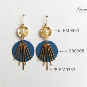 May include: A pair of gold-toned earrings with a pearl center and a navy blue disc. The earrings have gold-colored linear accents and a fish hook closure. The word "Sample" is written in cursive on the upper right.