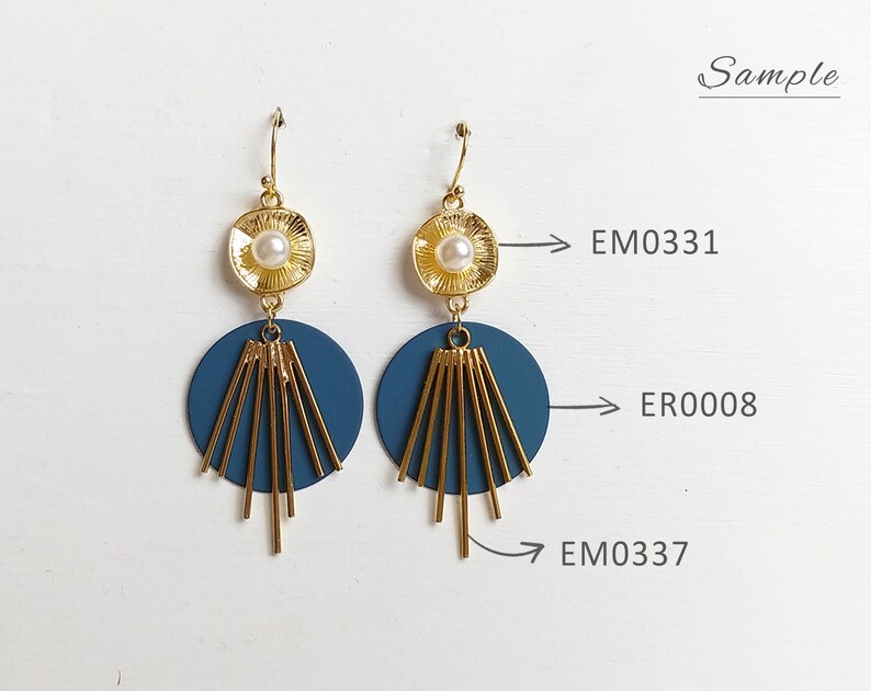 May include: A pair of gold-toned earrings with a pearl center and a navy blue disc. The earrings have gold-colored linear accents and a fish hook closure. The word "Sample" is written in cursive on the upper right.