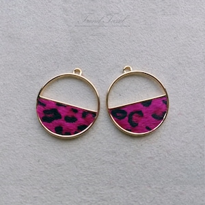 Pode incluir: Dois blanks circulares para brincos dourados com um design de estampa de leopardo rosa e preto na metade inferior de cada blank.
