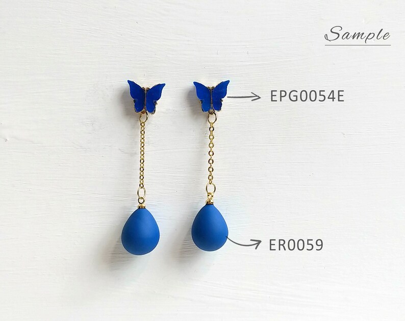 May include: A pair of blue butterfly earrings with gold-colored chains and teardrop-shaped pendants. The earrings are displayed on a white surface. The text "Sample" is in the upper right corner. The product codes are EPG0054E and ER0059.