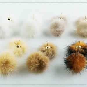 May include: Eight pairs of faux fur pom pom earrings in various colors, including white, beige, brown, and black. The earrings are made with a gold-colored post.