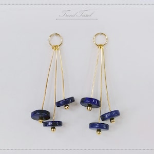 May include: Gold dangle earrings with three blue lapis lazuli stones on each earring.