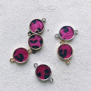 Puede incluir: Cinco abalorios conectores de oro y plata con diseños de estampado animal rosa y negro. Los abalorios tienen dos lazos para sujetar a joyas u otras manualidades.