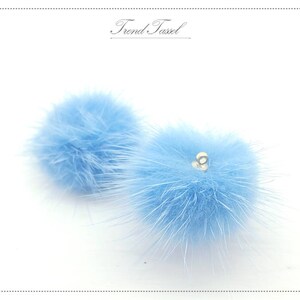 May include: Two light blue fluffy pom-poms with a silver loop attached to one of the pom-poms.