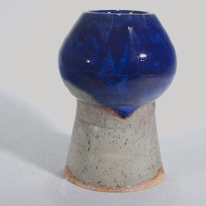 Könnte beinhalten: Eine blaue und weiße Keramikvase mit abgerundetem Oberteil und einem ausgestellten Fuß. Die Vase hat eine gesprenkelte Glasur und eine glatte, glänzende Oberfläche.