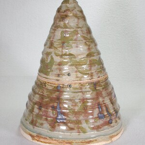 Könnte beinhalten: Eine konische, mit Deckel versehene Keramikdose mit brauner, grüner und weißer Glasur. Die Dose hat eine strukturierte Oberfläche und einen leicht abgerundeten Boden.