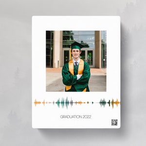 May include: A graduation photo of a person wearing a green cap and gown with a gold sash. The photo is in front of a building with a glass facade. The image includes a sound wave graphic and the text "GRADUATION 2022".