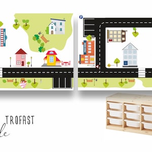 May include: Two white IKEA TROFAST storage units with white drawers, side by side. The units are in front of a black and white road map with a city scene featuring a fire station, school, houses, a church, a hospital, and a playground.