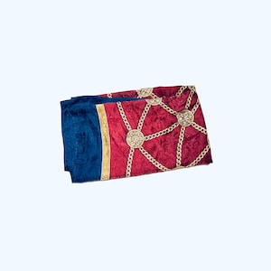 Puede incluir: Una bufanda de patr&oacute;n rojo y azul con cadenas doradas y dise&ntilde;os circulares.