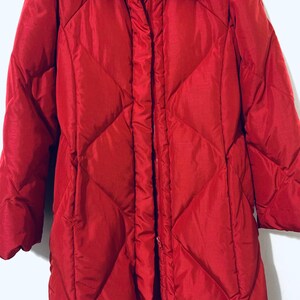 May include: A long, red quilted puffer coat with a high collar and a zipper closure.