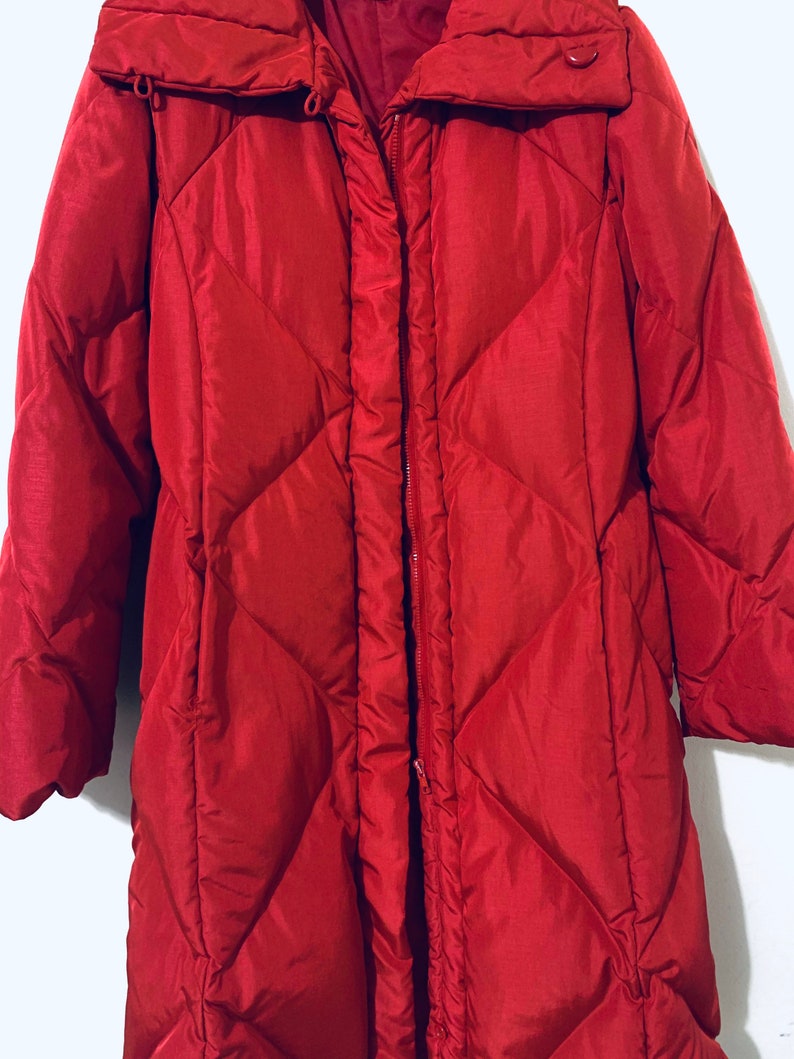 May include: A long, red quilted puffer coat with a high collar and a zipper closure.