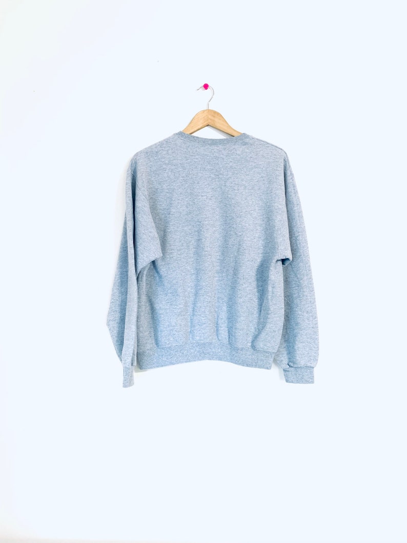 Puede incluir: Una sudadera gris jaspeada con mangas largas y cuello redondo.