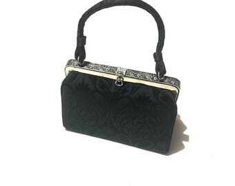 1950s black brocade handbag. Structured top handle bag with carved silver tone metal detail. Made in USA.