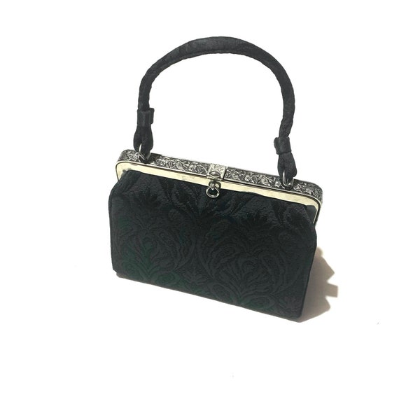 1950s black brocade handbag. Structured top handle bag with carved silver tone metal detail. Made in USA.