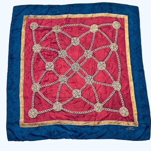 Puede incluir: Un pa&ntilde;uelo de seda rojo con un patr&oacute;n de cadena dorada y medallones. El pa&ntilde;uelo tiene un borde azul y el texto "Original Papell" en la esquina inferior derecha.