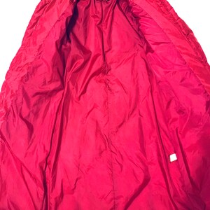 May include: Red puffer jacket with a zipper closure and a label that says "BRAEFAIR". The jacket is unzipped and the lining is visible.