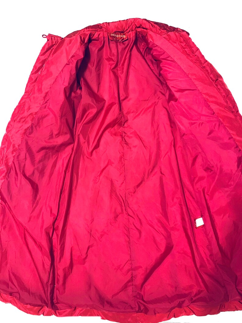 May include: Red puffer jacket with a zipper closure and a label that says "BRAEFAIR". The jacket is unzipped and the lining is visible.