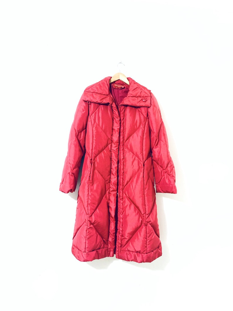 May include: A long, red quilted puffer coat with a stand-up collar and a zipper closure.