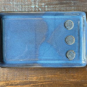 May include: A blue ceramic serving tray with three white spiral designs.