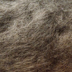 Könnte beinhalten: Nahaufnahme einer braunen und grauen Fellstruktur. Das Fell ist weich und flauschig mit einem leicht gewellten Muster.