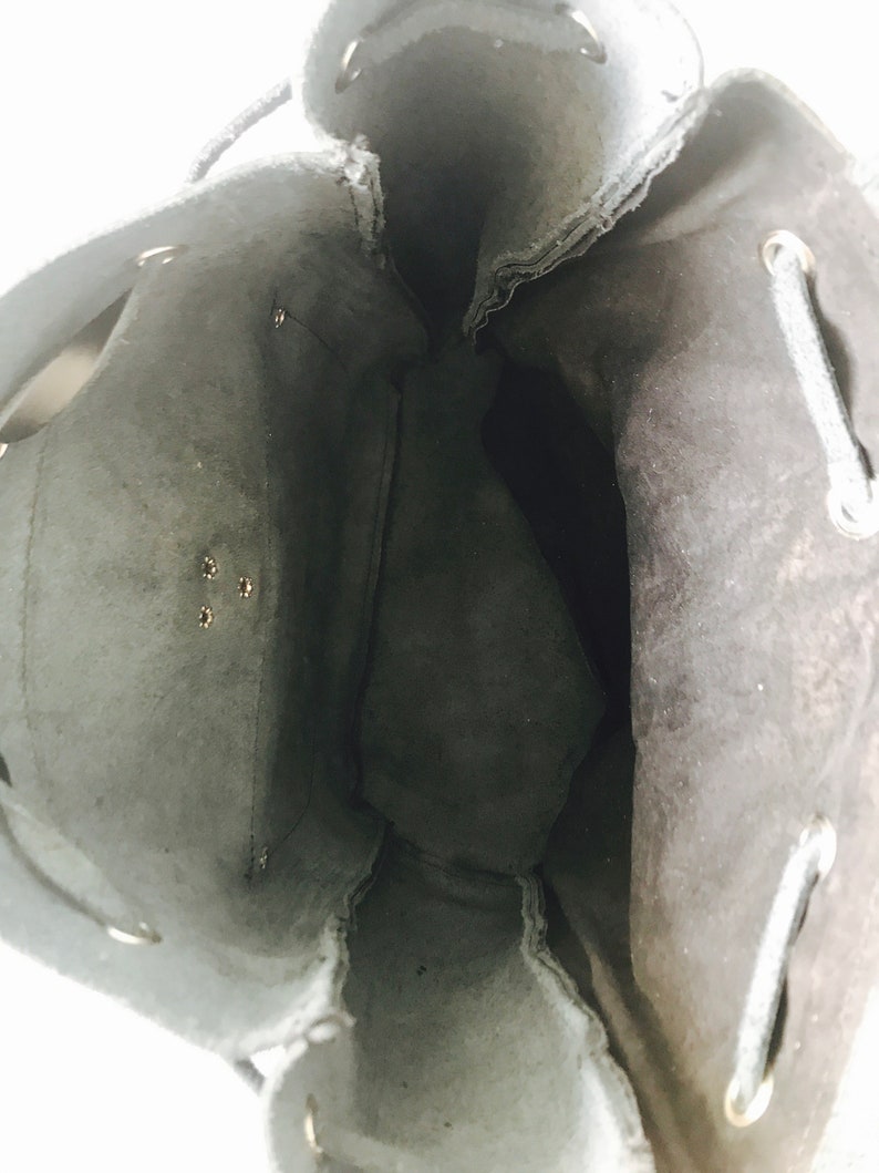 May include: Black drawstring bag with a suede-like texture and a single zipper pocket on the inside. The bag is empty and the drawstring is loose.