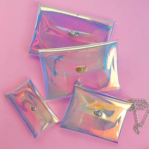 May include: Four iridescent clear plastic bags with silver clasps. The bags are different sizes and one has a silver chain attached.