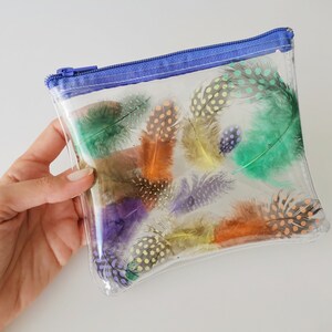 Puede incluir: Una bolsa de pl&aacute;stico transparente con cremallera azul y una variedad de plumas coloridas con lunares en el interior.