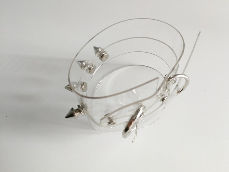 May include: A clear plastic bracelet with silver spikes and a silver clasp.