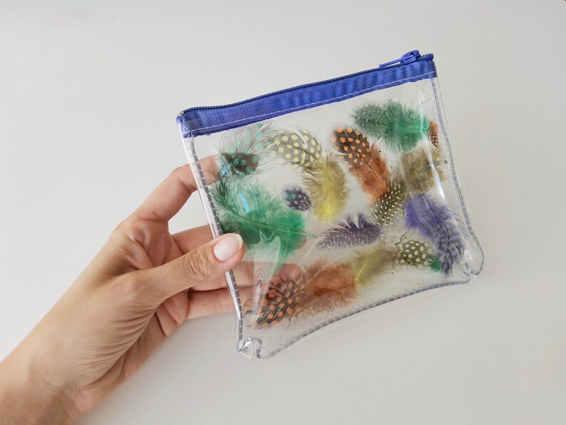 Puede incluir: Una bolsa transparente de pl&aacute;stico con cremallera azul y una variedad de plumas de colores en su interior.
