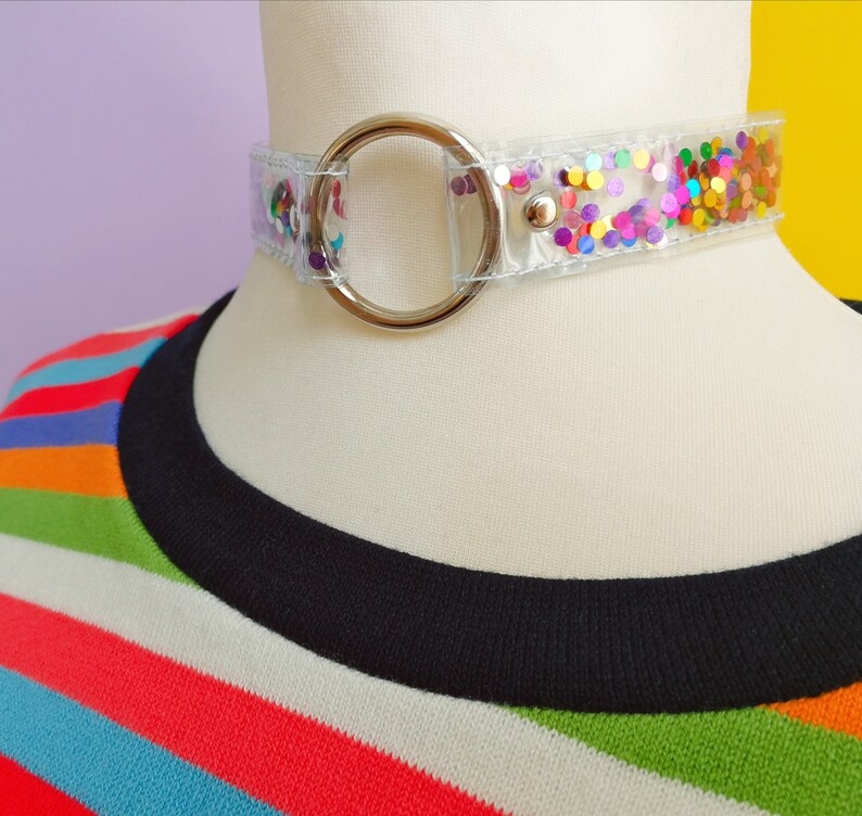Op de afbeelding: Een transparante choker ketting met een zilveren ring sluiting. De ketting is versierd met kleurrijk confetti.