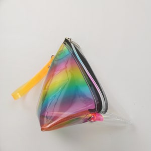 May include: A clear, iridescent rainbow-colored zippered pouch with a yellow strap. The pouch is shaped like a triangle.