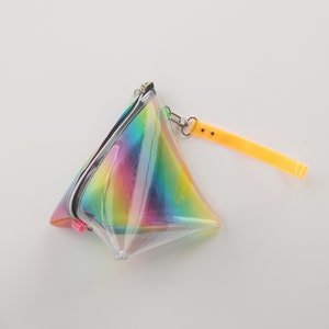 May include: A clear iridescent rainbow triangle-shaped pouch with a zipper closure and a yellow strap.