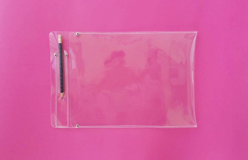 May include: A clear plastic document holder with a pencil in a pocket, set against a bright pink background. The holder has a rectangular shape with rounded corners and is secured with metal rivets.