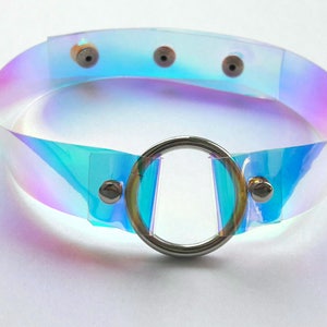 May include: A iridescent clear plastic choker with a silver ring and silver snaps.