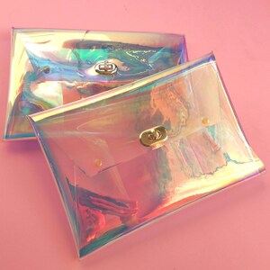 May include: Two iridescent clear plastic clutch purses with gold clasps. The purses are stacked on top of each other.