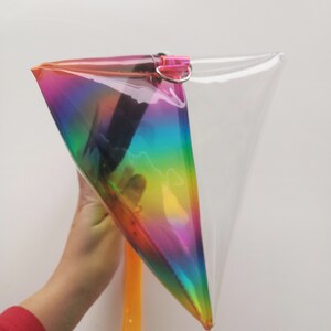 May include: A clear plastic rainbow iridescent pouch with a zipper closure and a yellow strap.