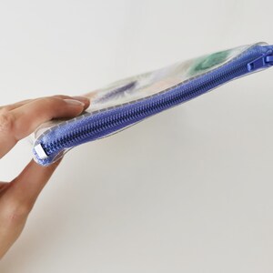 Puede incluir: Una bolsa de pl&aacute;stico transparente con cremallera y un dise&ntilde;o abstracto de colores. La cremallera es morada.