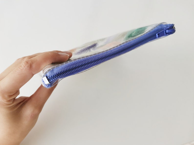 Puede incluir: Una bolsa de pl&aacute;stico transparente con cremallera y un dise&ntilde;o abstracto de colores. La cremallera es morada.
