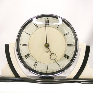 May include: A white ceramic mug with a black handle and the text "But First, Coffee" in a black, bold font. The mug is on a white surface.