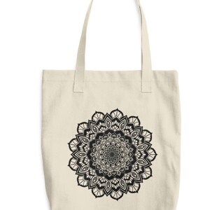 May include: A beige canvas tote bag with a black and white mandala design printed on the front.