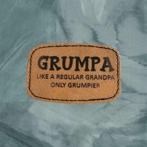 May include: A brown leather patch with the text "Grumpa Like a Regular Grandpa Only Grumpier" in black lettering.