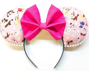 May include: Pink Minnie Mouse ears with a pink bow and a fabric design featuring various dog breeds, including Dalmatians, on a pink background with white paw prints.