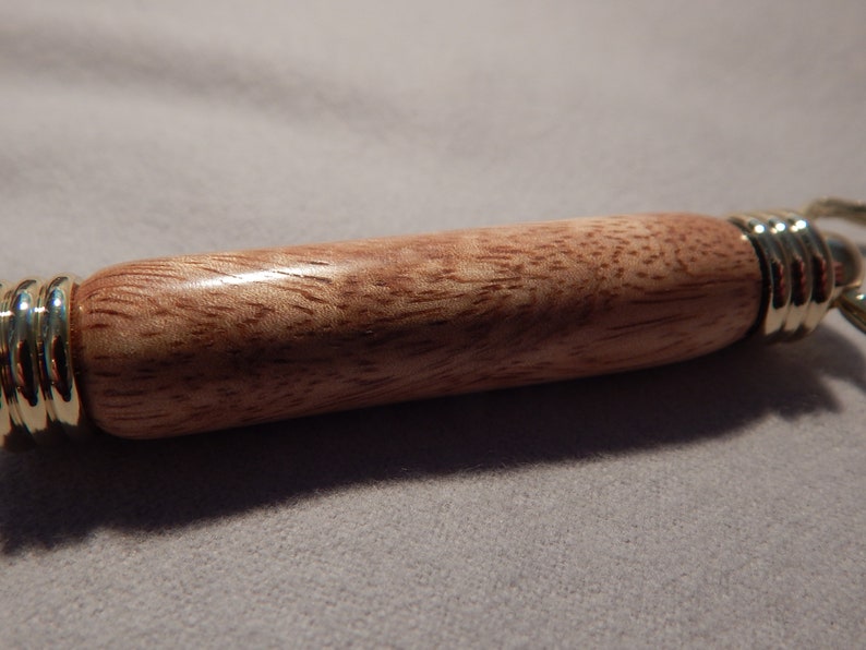 May include: A wooden keychain with a brown and pink wood grain pattern and gold metal accents.