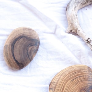 May include: Four wooden coasters with a natural wood grain pattern. The coasters are round and have a smooth, polished finish.
