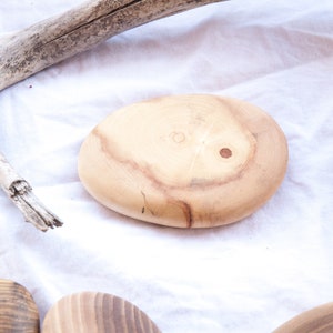May include: Four wooden coasters in various shades of brown, with a natural wood grain pattern. The coasters are oval shaped and have a smooth, polished finish.