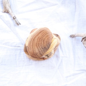 May include: A set of three wooden bowls stacked on top of each other. The bowls are made of light brown wood with a natural grain pattern. The bowls are round and have a slightly curved shape.