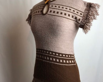 May include: A brown and beige knitted sweater with a geometric pattern and fringe trim. The sweater has a keyhole neckline with a wooden button.