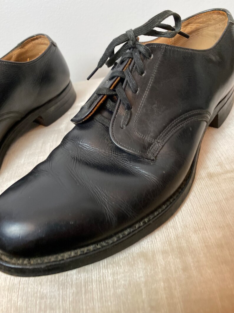 May include: A pair of black leather lace-up shoes with a rounded toe and a low heel.